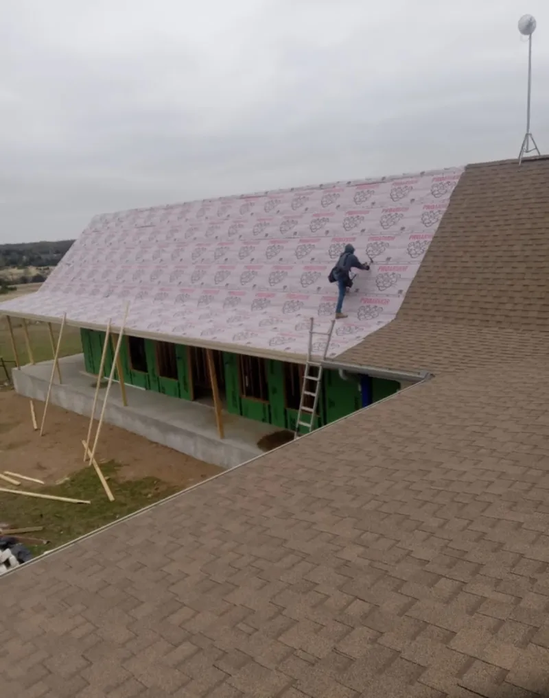 Worker preparing underlayment for a metal roof installation in Columbia